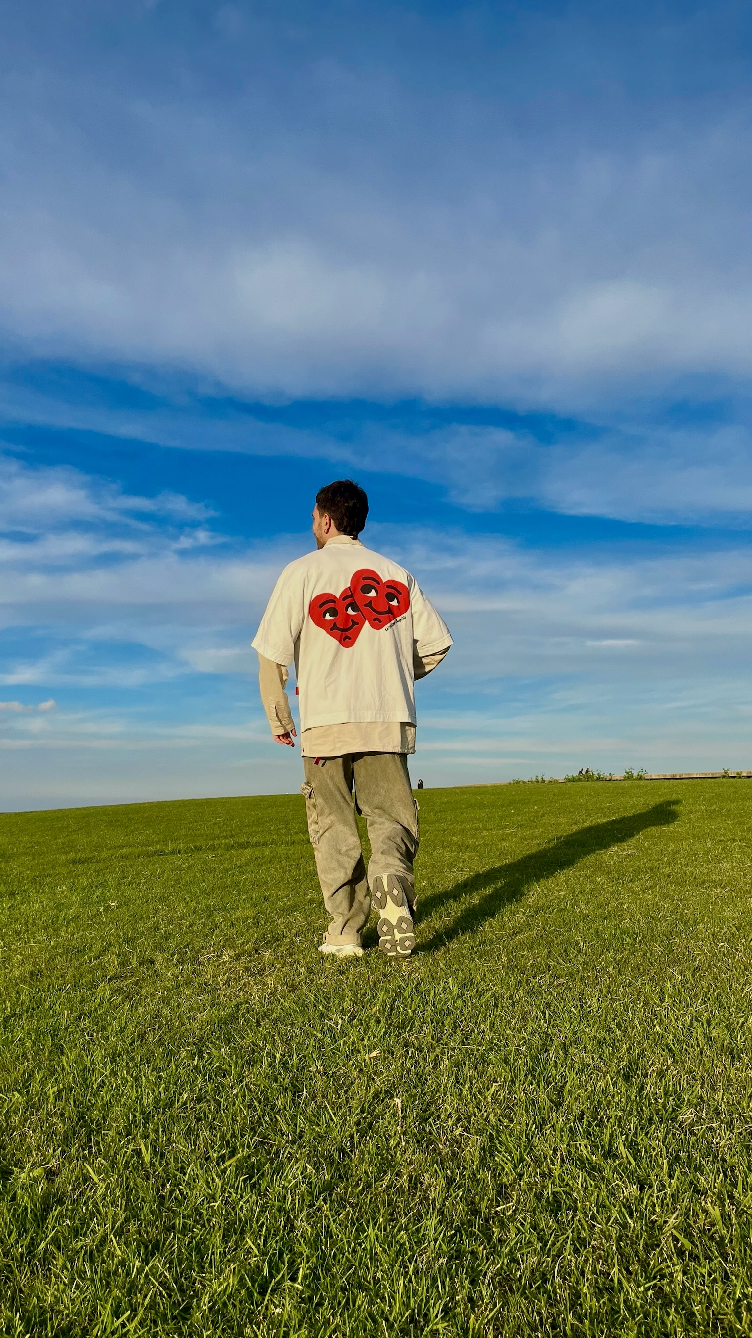 A person walking in a grassy field under a blue sky